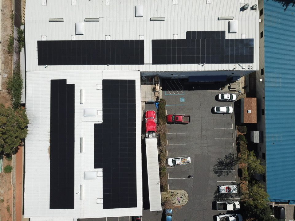 An aerial view of a commercial building with an extensive solar panel system installed on the roof, maximizing energy efficiency.