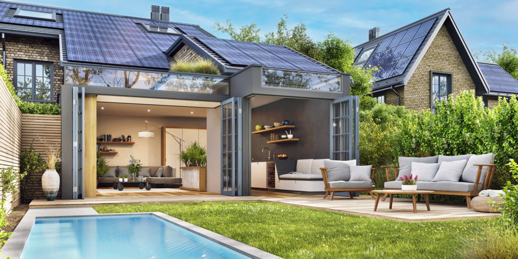 A contemporary home with large solar panels on the roof, an open-concept indoor-outdoor living space, and a landscaped backyard with seating and greenery.