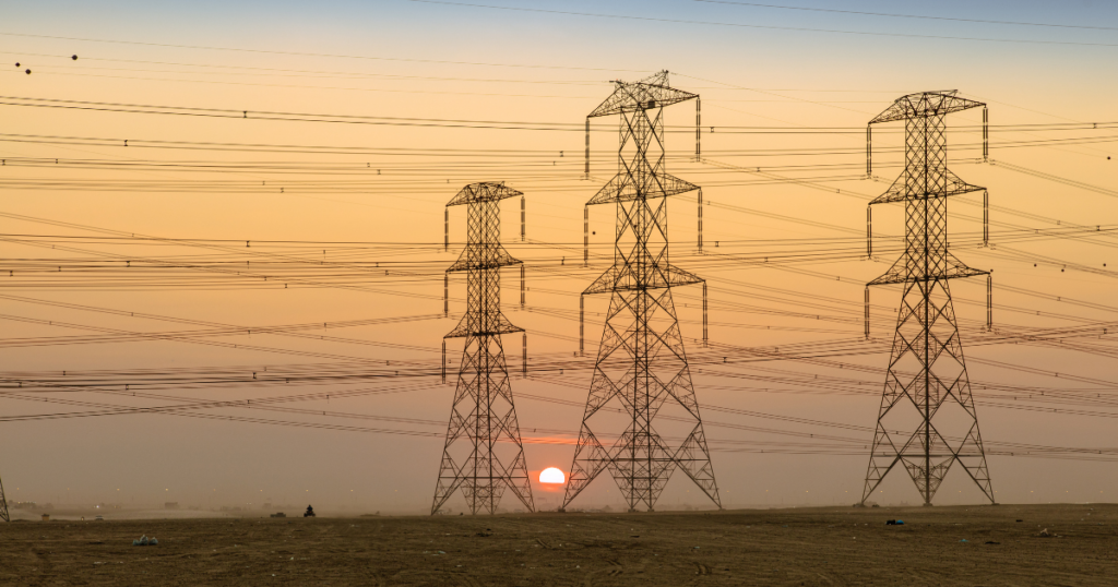 Electrical transmission towers with hazy sunset in background.